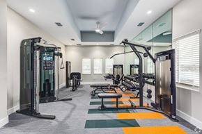 Wildwood triplex for rent - a gym with cardio equipment and mirrors in a building with white walls