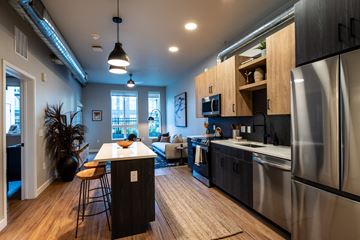 Denver apartment for rent - an open kitchen and living room with stainless steel appliances and a table