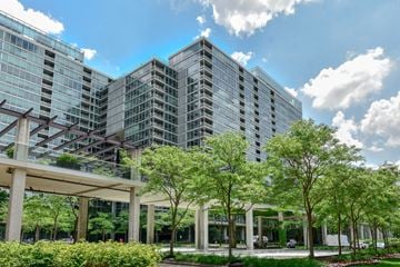 Skokie apartment for rent - A modern building with glass windows and a green lawn in front.