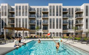 Lynn apartment for rent - People are enjoying a sunny day at the pool in front of a modern apartment building.