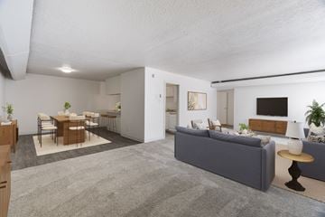 Albuquerque apartment for rent - A living room with a grey sofa, a dining table with chairs, and a TV on the wall.