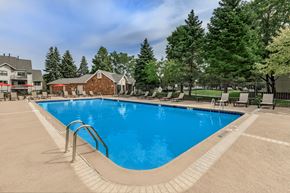 Aurora apartment for rent - A large outdoor swimming pool surrounded by trees and a building.