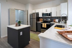 Lenexa apartment for rent - a kitchen with white cabinetry and black appliances