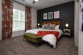 Lenexa apartment for rent - a bedroom with a bed and a chair in front of a window
