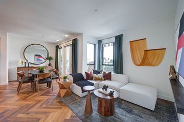 West Hollywood apartment for rent - A modern living room with a white sofa, wooden coffee table, and a large abstract painting on the wall.