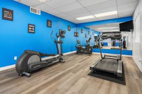 Tucson apartment for rent - a gym with various exercise machines and a blue wall