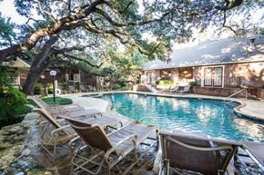 San Antonio apartment for rent - a pool with lounge chairs and a house in the background