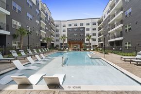 Houston apartment for rent - A pool surrounded by lounge chairs and apartment buildings. at Alta Sunset Heights, Houston, 77009