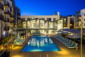 Los Angeles apartment for rent - A swimming pool surrounded by lounge chairs and umbrellas at night.