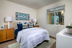 Rancho Cucamonga apartment for rent - A bedroom with a bed, two lamps, a painting, and a mirror.