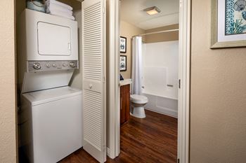Small bathroom with a washer and dryer in it and a white toilet