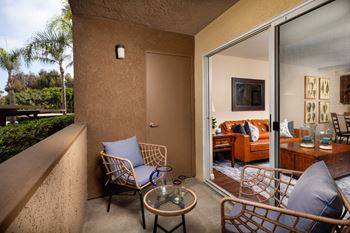 Balcony with two chairs and a table and a sliding glass door