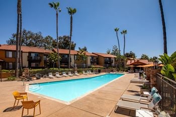 Swimming pool with chairs and trees and buildings in the background
