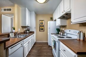 Vista apartment for rent - A kitchen with white cabinets and a fridge.
