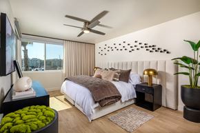 Marina Del Rey apartment for rent - A bedroom with a bed, a fan, and a window with a view of a city.