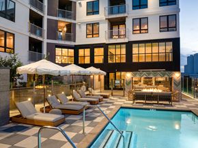 Los Angeles apartment for rent - A large, modern building with a pool and lounge chairs.