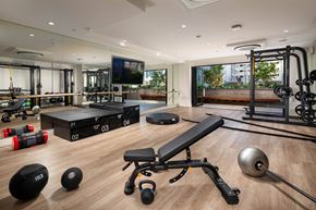 Los Angeles apartment for rent - A gym with a variety of equipment including a bench, kettlebell, and a barbell.