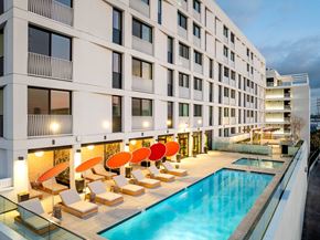 Los Angeles apartment for rent - A modern building with a pool and loungers.