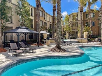 Resort-style pool with open air cabanas with palm trees in front of lounge