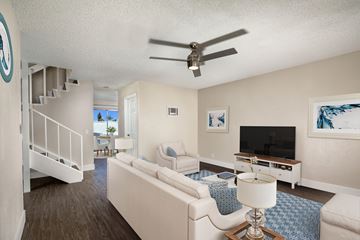 Oceanside apartment for rent - A living room with a white couch and a ceiling fan.