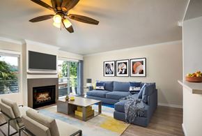 Woodland Hills apartment for rent - A living room with a fireplace, a grey couch, and a ceiling fan.