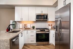 San Diego apartment for rent - A modern kitchen with white cabinets and stainless steel appliances.