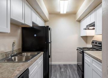Kennesaw apartment for rent - a kitchen with white cabinets and a black refrigerator