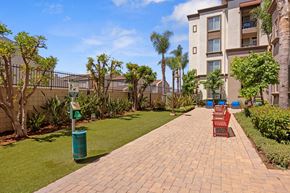 Torrance apartment for rent - A brick walkway leads to a building with a green trash can on the side.