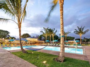 Kapolei apartment for rent - a swimming pool with palm trees and chairs around it