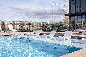 Aurora apartment for rent - A pool with white chairs and a building in the background.