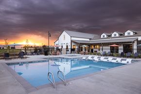 Loveland apartment for rent - A swimming pool in front of a building with a sunset in the background.