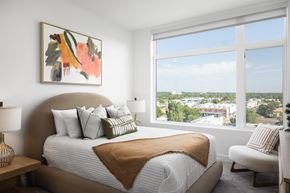 Denver apartment for rent - A bedroom with a large bed and a view of the city.