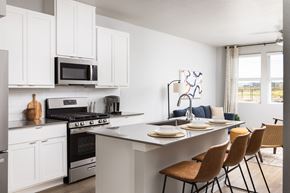 Broomfield townhouse for rent - an open kitchen and dining area with white cabinets and a table with chairs