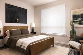 Parker apartment for rent - A bedroom with a large bed, a chair, and a painting on the wall.