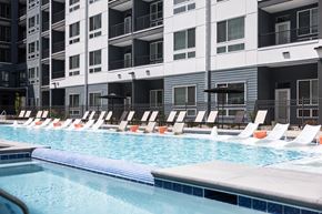 Denver apartment for rent - A swimming pool with lounge chairs in front of apartment buildings.
