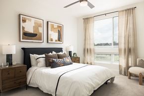 Denver apartment for rent - A bedroom with a large bed, a ceiling fan, and two abstract paintings on the wall.