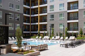 Lakewood apartment for rent - a pool with lounge chairs in front of an apartment building