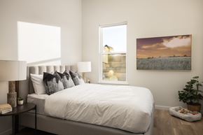 Aurora apartment for rent - A bedroom with a large bed, a lamp, a potted plant, and a painting on the wall.