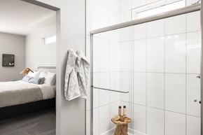 Aurora townhouse for rent - A bathroom with a white tiled shower and a bedroom with a bed and a nightstand.