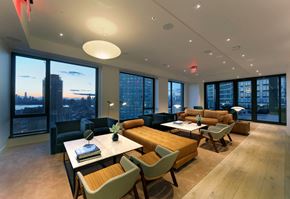 Long Island City apartment for rent - a lounge area with couches tables and chairs and large windows