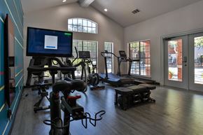 San Antonio apartment for rent - A gym with exercise equipment and a television displaying a webpage at The Quarry Alamo Heights Apartments, Texas, 78209