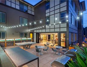 Bothell apartment for rent - A patio with a pool table and chairs is lit up with string lights.