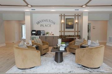 St. Louis apartment for rent - A living room with a coffee table and chairs in front of a sign that says Irvington Place.