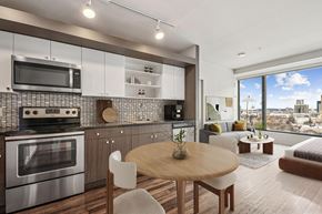 Boston apartment for rent - A modern kitchen with a wooden table and chairs, a stainless steel oven, and a microwave above the stove.