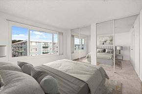 Daly City apartment for rent - A bedroom with a large bed and a view of a building outside the window.