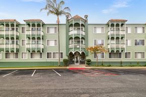 Daly City apartment for rent - A green apartment building with a palm tree in front.