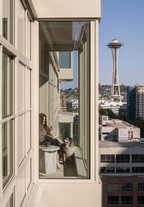 Seattle apartment for rent - A woman is sitting at a table with her dog in a room with a view of the Space Needle.