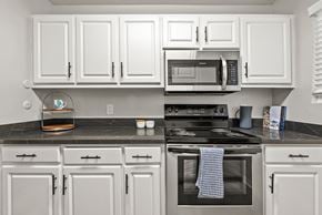 Sacramento apartment for rent - A kitchen with white cabinets and a black stove top.