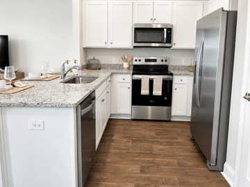 Summerville townhouse for rent - A kitchen with a stainless steel refrigerator, a microwave above the stove, and a sink with a granite countertop.