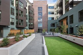 Oakland apartment for rent - an image of an apartment complex with green grass and a patio